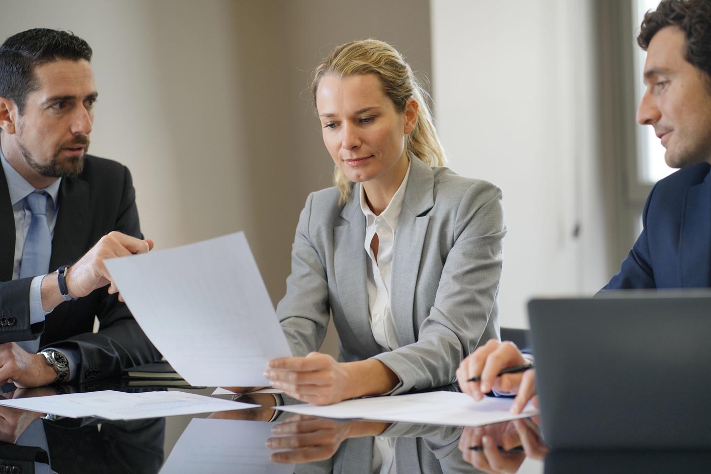 Verhandlung einer Abfindung zwischen eine Frau und zwei Männern im Business-Outfit